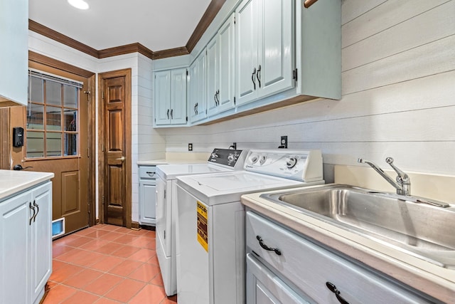 laundry area featuring washing machine and clothes dryer, sink, cabinets, light tile patterned floors, and ornamental molding