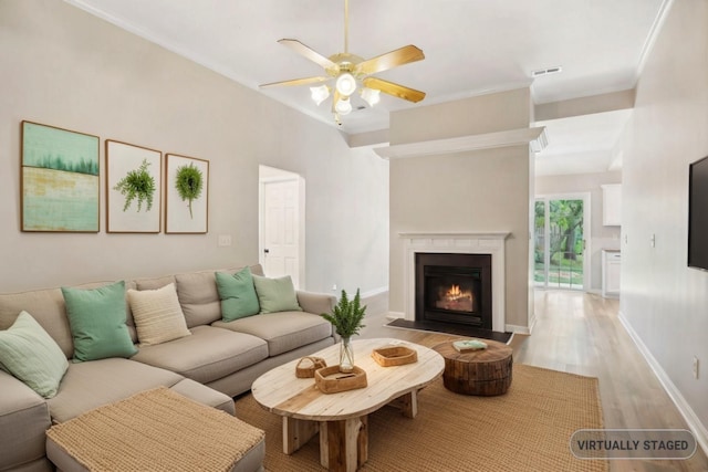 living room with ceiling fan, ornamental molding, and light hardwood / wood-style flooring