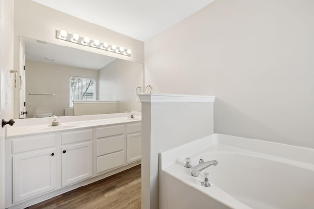 bathroom featuring a washtub, vanity, hardwood / wood-style flooring, and toilet