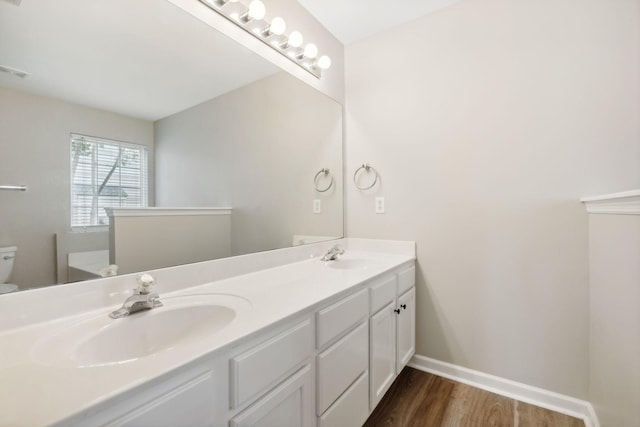 bathroom with hardwood / wood-style floors, vanity, and toilet