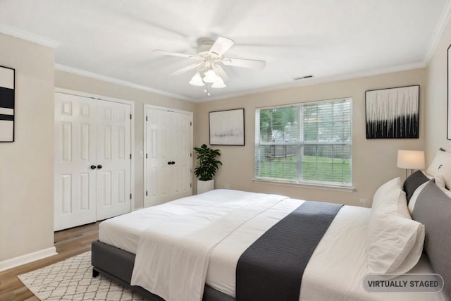 bedroom with multiple closets, ceiling fan, wood-type flooring, and ornamental molding