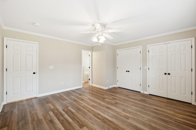 unfurnished bedroom featuring ceiling fan, crown molding, hardwood / wood-style floors, and two closets