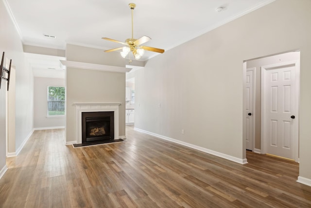 unfurnished living room with ceiling fan, ornamental molding, and dark wood-type flooring