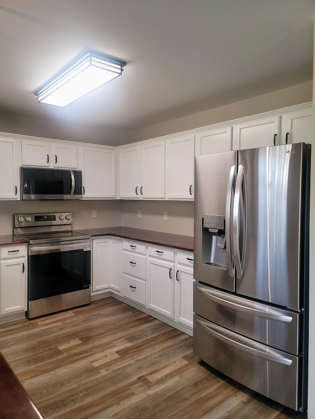 kitchen with white cabinets, wood-type flooring, and appliances with stainless steel finishes