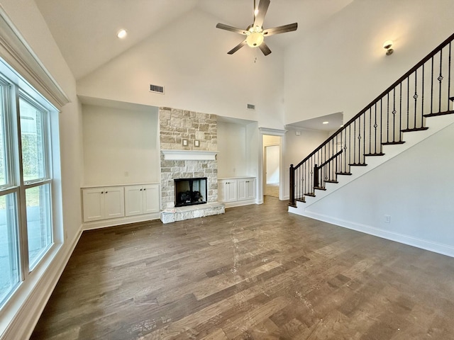 unfurnished living room featuring dark hardwood / wood-style floors, ceiling fan, a fireplace, and high vaulted ceiling