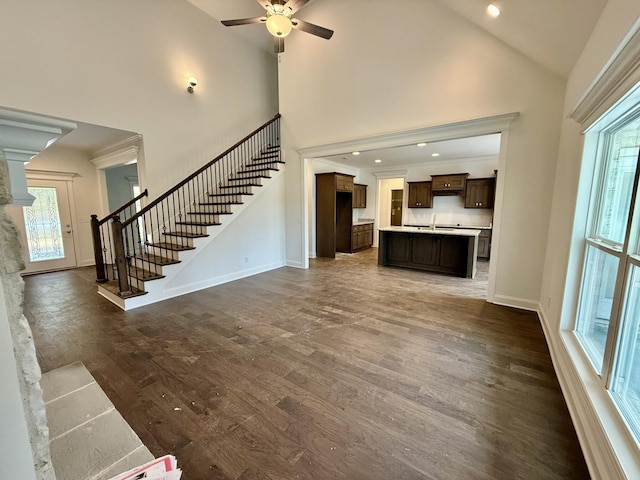 unfurnished living room with ceiling fan, a healthy amount of sunlight, dark wood-type flooring, and high vaulted ceiling