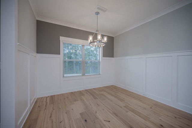 unfurnished dining area with light hardwood / wood-style flooring, ornamental molding, and an inviting chandelier