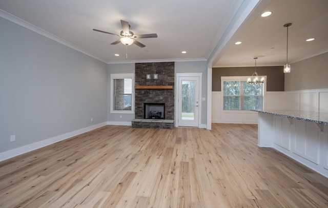 unfurnished living room with light hardwood / wood-style flooring, a stone fireplace, and crown molding