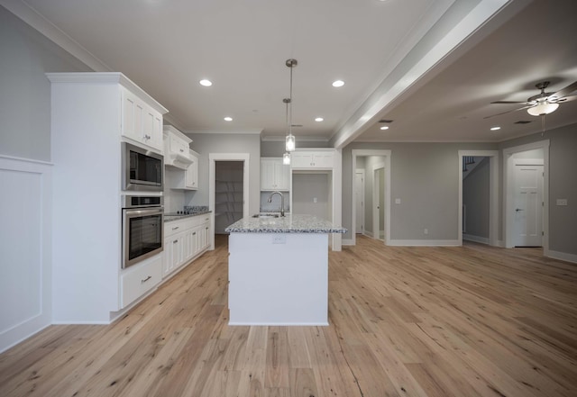 kitchen featuring white cabinets, an island with sink, light stone counters, and stainless steel oven