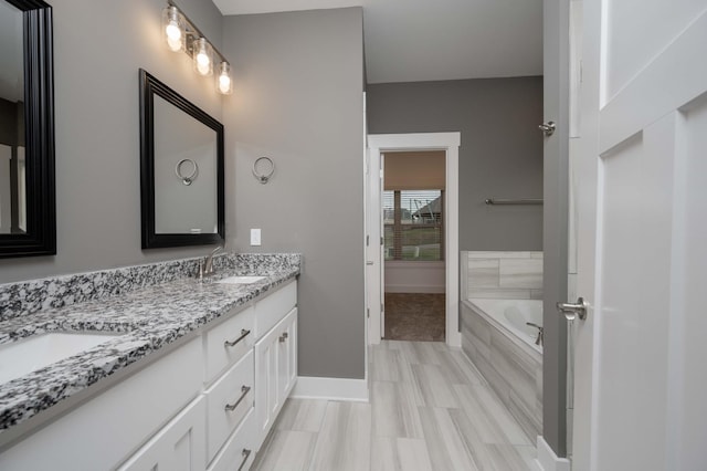 bathroom featuring a relaxing tiled tub and vanity