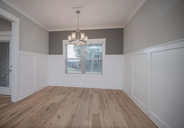 unfurnished dining area featuring light hardwood / wood-style flooring, an inviting chandelier, and crown molding