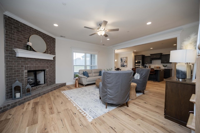 living room with a fireplace, ceiling fan, light hardwood / wood-style flooring, and ornamental molding