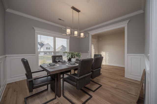 dining space featuring hardwood / wood-style flooring, crown molding, and a chandelier