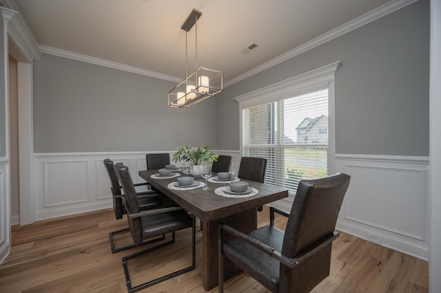 dining space with hardwood / wood-style floors, a notable chandelier, and crown molding