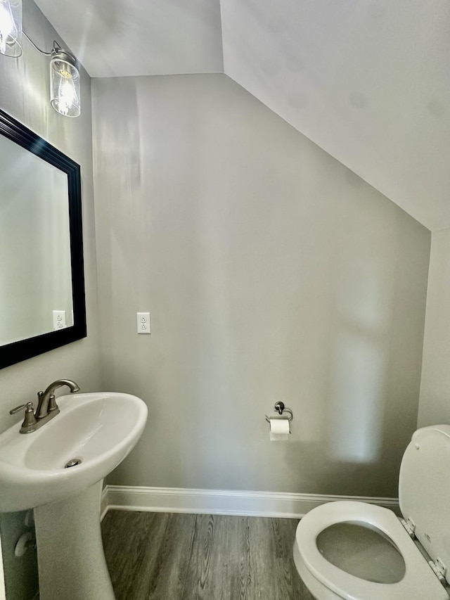 bathroom featuring hardwood / wood-style flooring, sink, lofted ceiling, and toilet