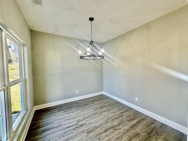 unfurnished dining area featuring dark hardwood / wood-style flooring and an inviting chandelier