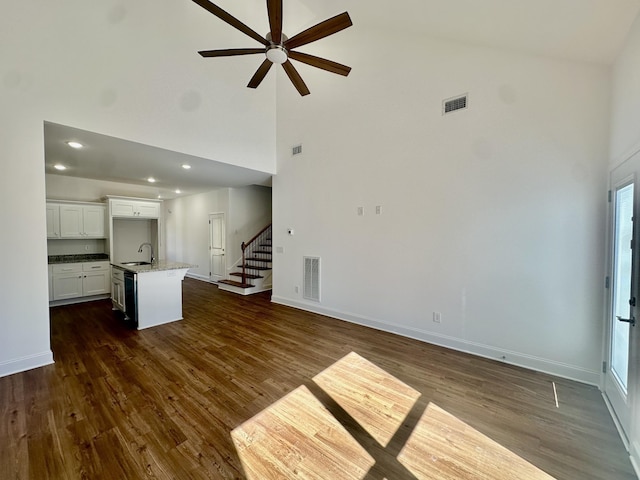 unfurnished living room featuring ceiling fan, dark hardwood / wood-style floors, sink, and high vaulted ceiling