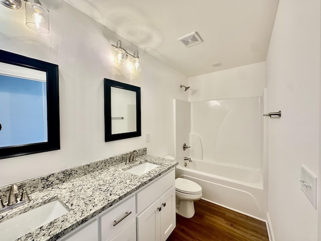 full bathroom featuring vanity, hardwood / wood-style floors, washtub / shower combination, and toilet