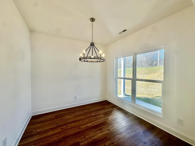 unfurnished dining area featuring dark hardwood / wood-style floors, an inviting chandelier, and lofted ceiling