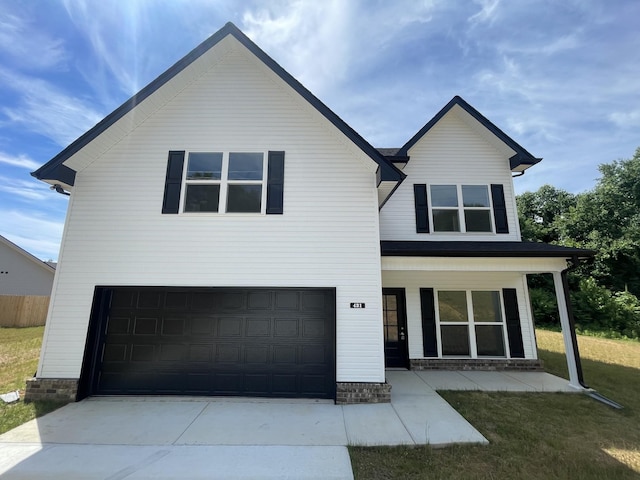 view of front of property featuring covered porch, a garage, and a front lawn