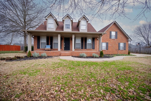 new england style home with a front yard and covered porch