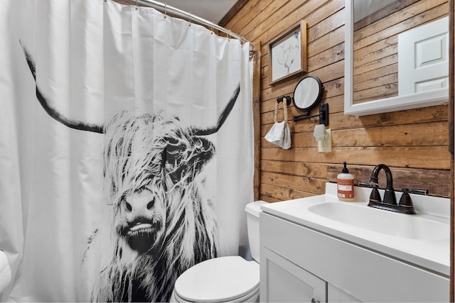 bathroom with vanity, wood walls, and toilet