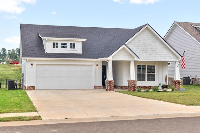 craftsman-style house with a garage, a front yard, cooling unit, and covered porch