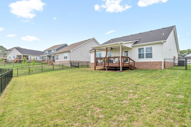 rear view of property featuring ceiling fan, a yard, and a wooden deck