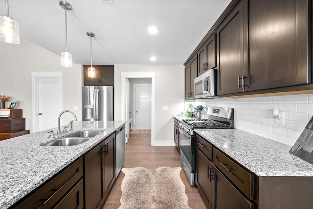 kitchen with appliances with stainless steel finishes, light stone counters, decorative light fixtures, and sink