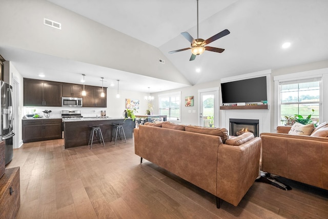 living room featuring lofted ceiling, ceiling fan with notable chandelier, and dark hardwood / wood-style floors