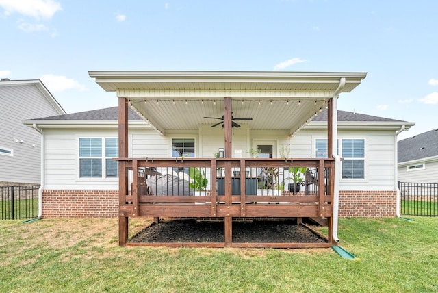 back of property with ceiling fan, a wooden deck, and a lawn