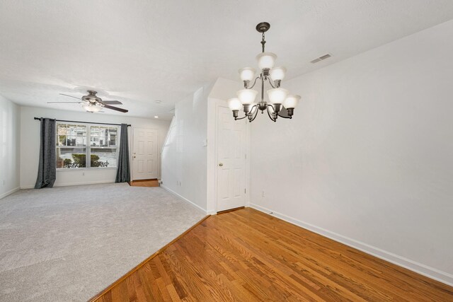 spare room with hardwood / wood-style flooring and ceiling fan with notable chandelier