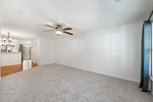 carpeted spare room featuring a textured ceiling and ceiling fan with notable chandelier