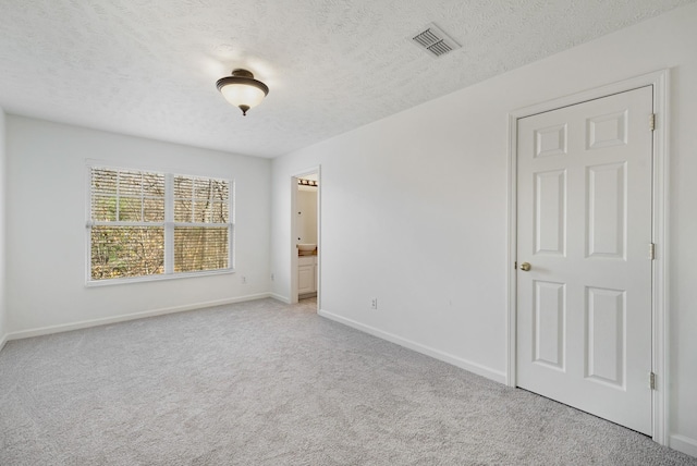 spare room with light carpet and a textured ceiling