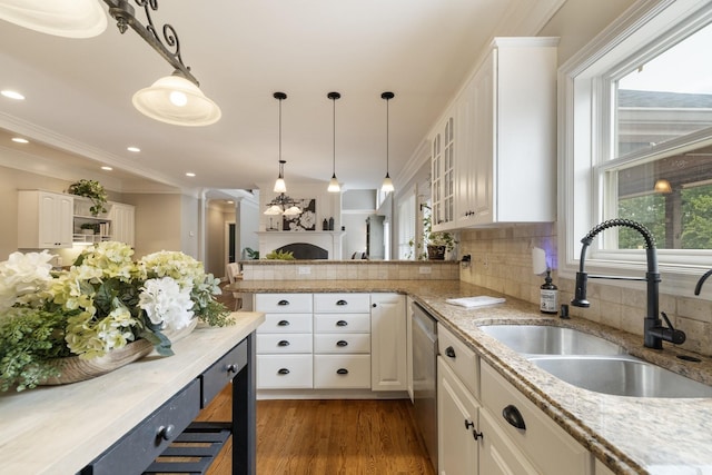 kitchen featuring decorative light fixtures, white cabinetry, stainless steel dishwasher, and sink