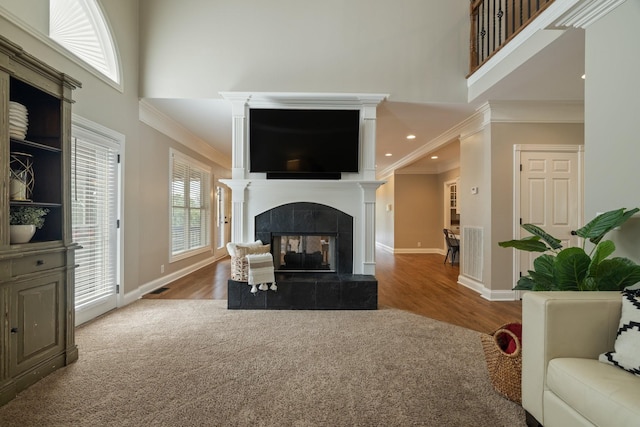 carpeted living room with a tile fireplace and ornamental molding