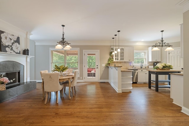 dining space with a tile fireplace, crown molding, hardwood / wood-style floors, and sink