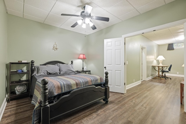 bedroom with hardwood / wood-style floors, a paneled ceiling, and ceiling fan