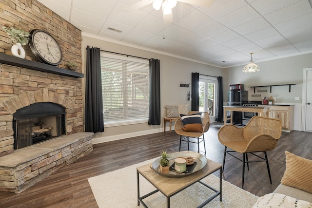 living room with ceiling fan, ornamental molding, a fireplace, and dark wood-type flooring