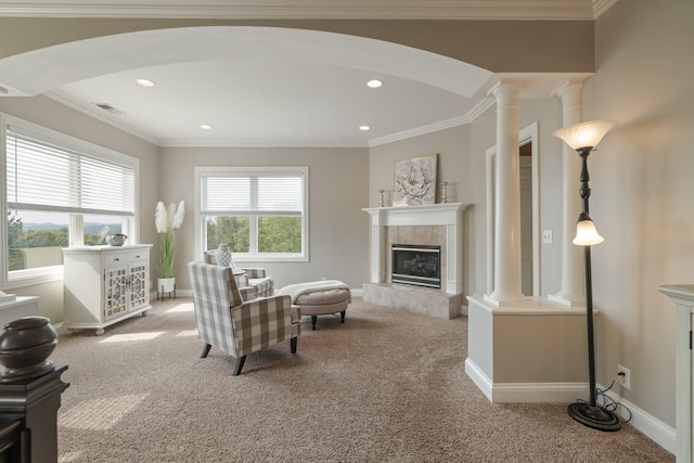 living room with decorative columns, a tiled fireplace, light carpet, and crown molding