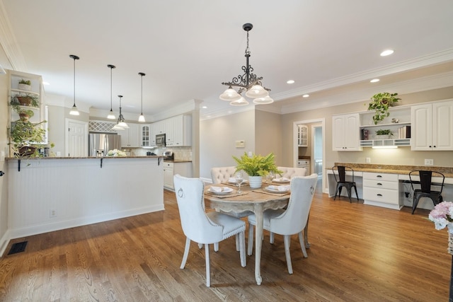 dining space featuring hardwood / wood-style floors, crown molding, and a chandelier