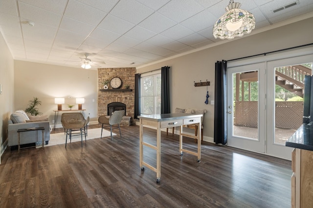 interior space with a fireplace, ornamental molding, ceiling fan, and dark wood-type flooring