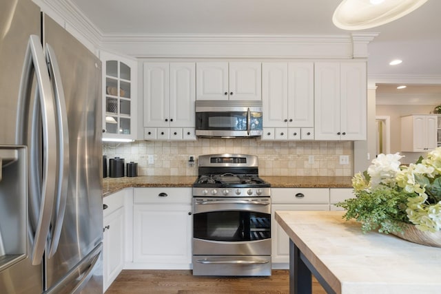 kitchen with backsplash, white cabinets, dark hardwood / wood-style floors, ornamental molding, and appliances with stainless steel finishes