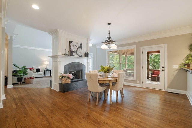 dining room featuring a chandelier, crown molding, a fireplace, and hardwood / wood-style floors