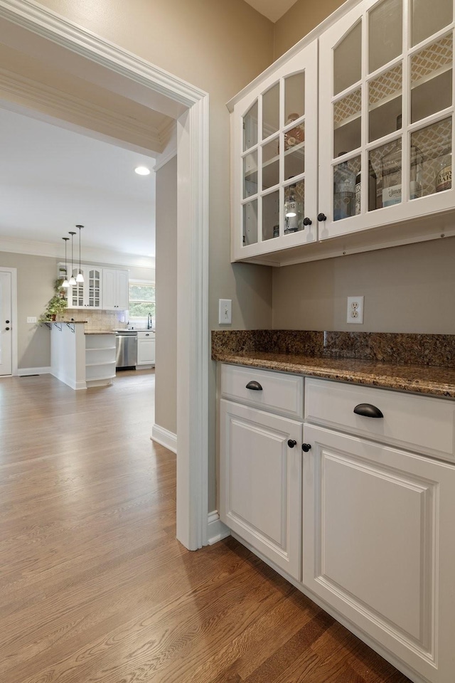 bar with white cabinets, dishwasher, crown molding, and hanging light fixtures