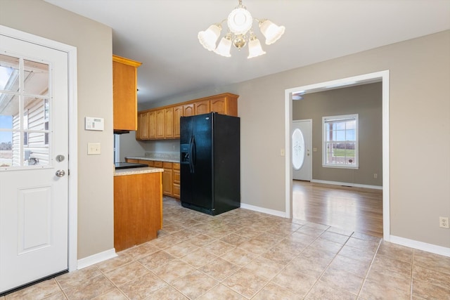 kitchen with black fridge with ice dispenser, light tile patterned floors, and an inviting chandelier