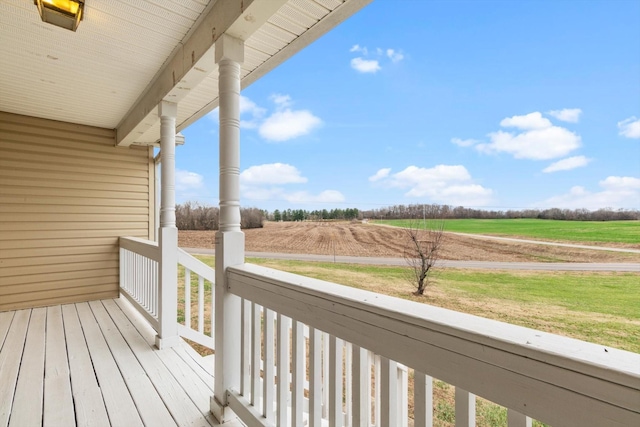 deck featuring covered porch and a rural view