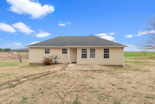 rear view of house featuring a lawn, a rural view, and a patio area