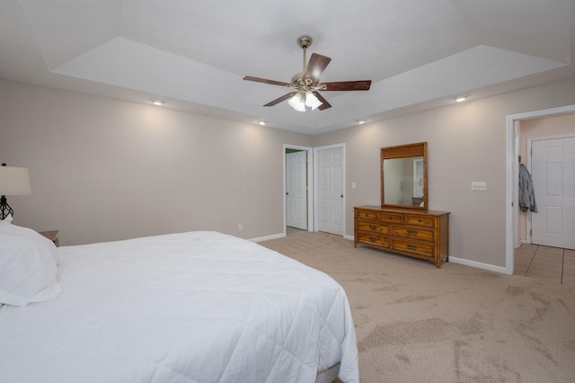 bedroom with a raised ceiling, ceiling fan, and light carpet