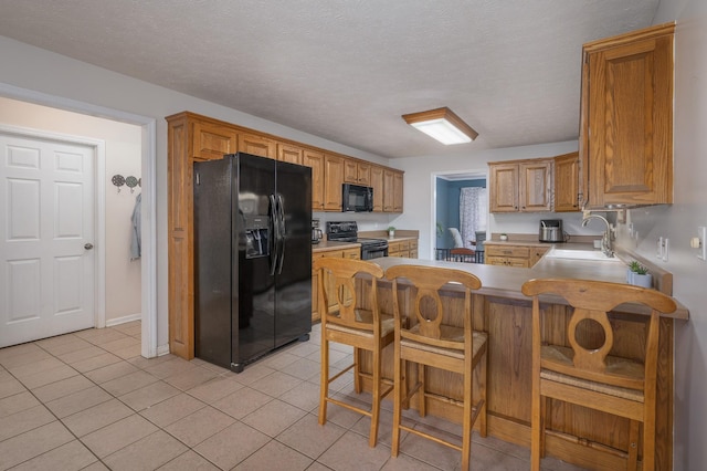 kitchen featuring kitchen peninsula, sink, black appliances, and a textured ceiling